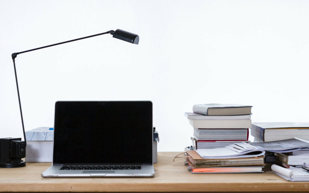 Schreibtisch mit Laptop, Büchern und OrdnernSchreibtisch mit Laptop, Büchern und Ordnern