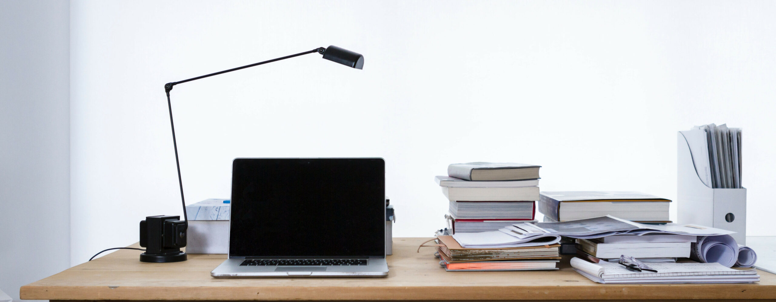 Schreibtisch mit Laptop, Büchern und OrdnernSchreibtisch mit Laptop, Büchern und Ordnern