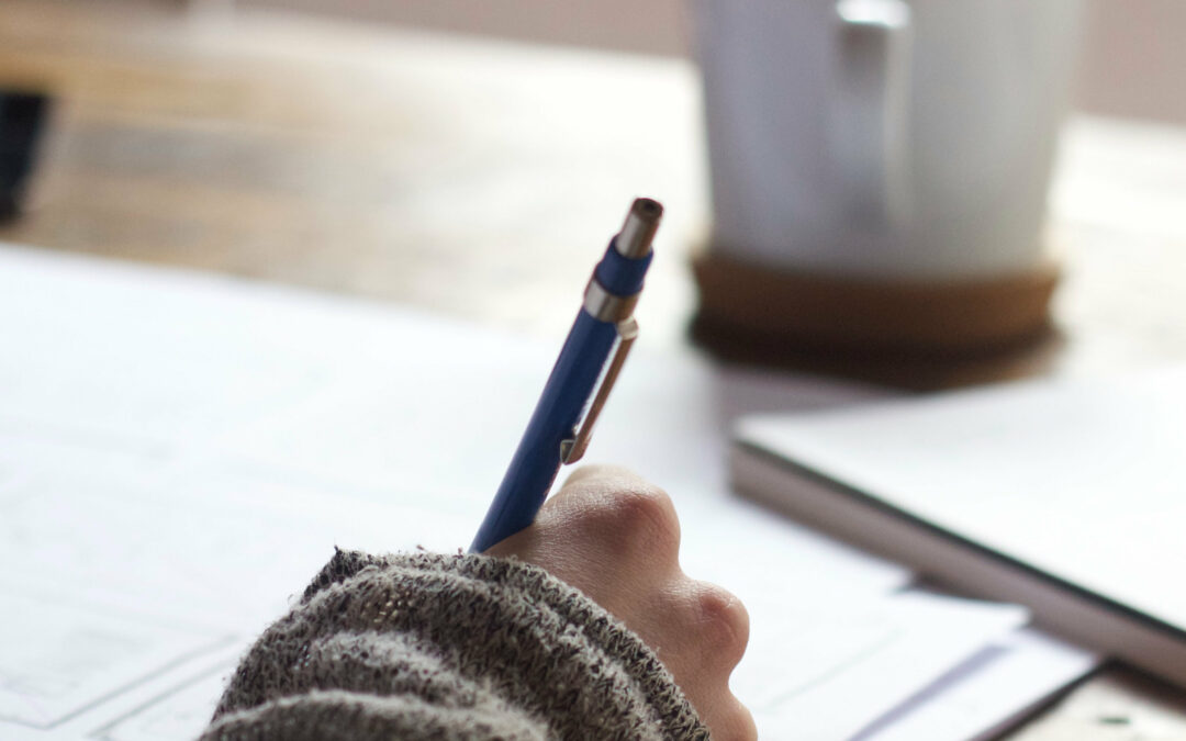 Hand hält Stift und schreibt auf Papier