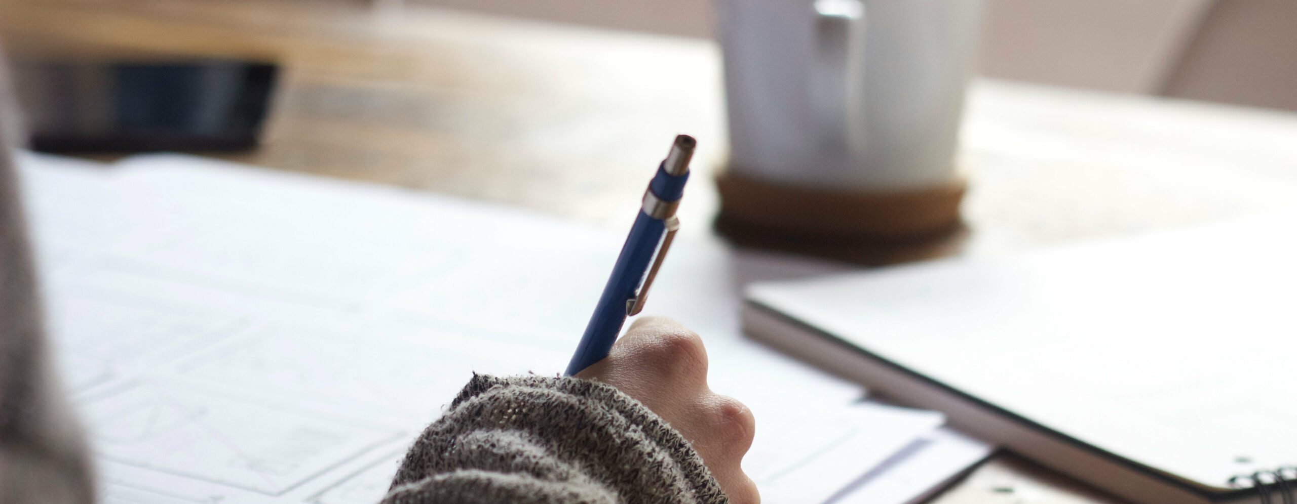 Hand hält Stift und schreibt auf Papier