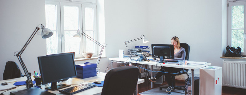 Abschlussbericht: Mein PR-Praktikum bei factum Mitarbeiterin sitzt an Schreibtisch in der Agentur