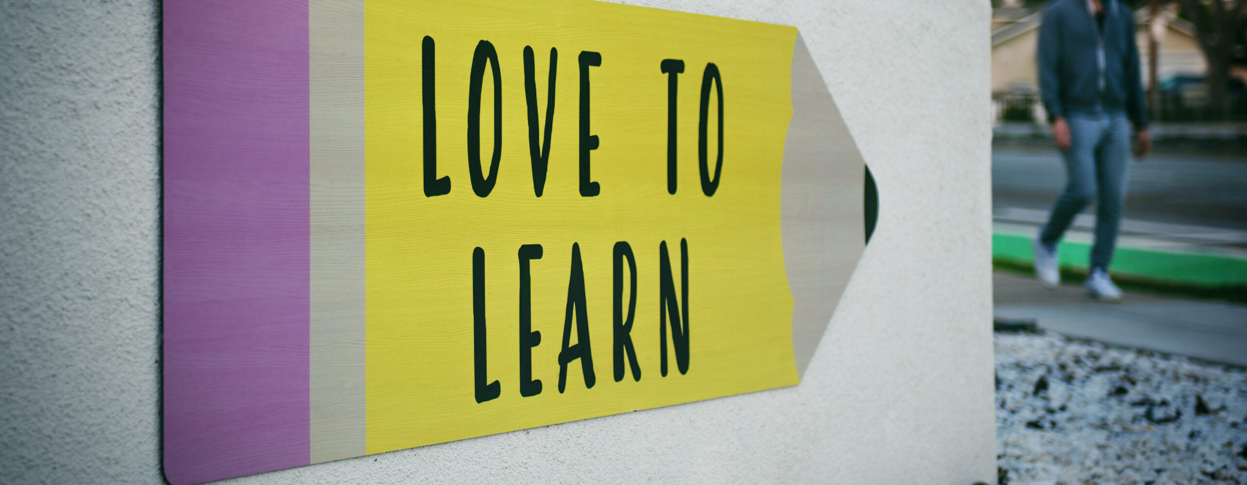 Schild eines Bleistifts mit der Aufschrift "Love to learn"