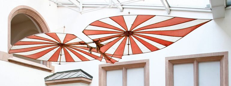 Fluggert Rathaus Pano c Stadtarchiv Ulm verkleideter Mann mit Zylinder und gebastelten Flügeln sitzt am Wasser