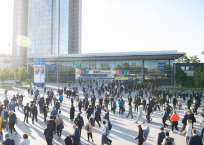 Blick auf den Eingang des Messegeländes der EMO Hannover mit vielen umhergehenden Menschen