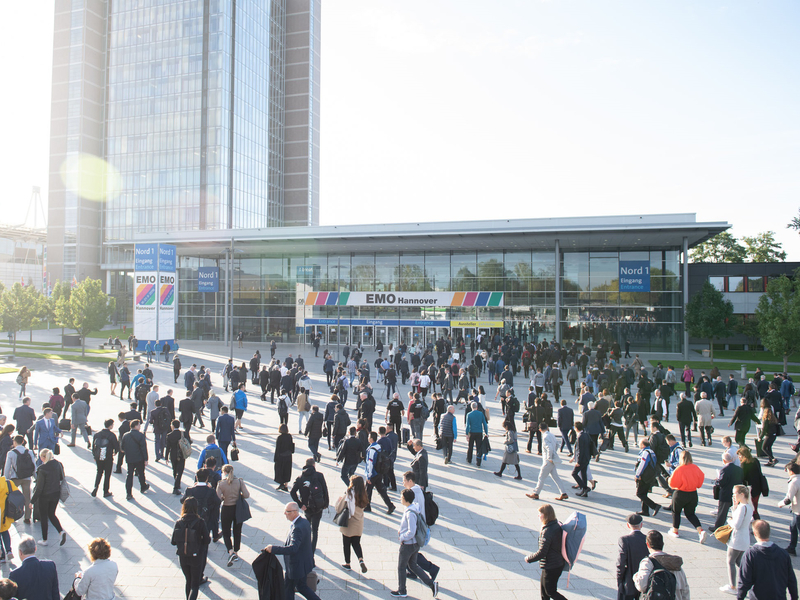 Blick auf den Eingang des Messegeländes der EMO Hannover mit vielen umhergehenden Menschen