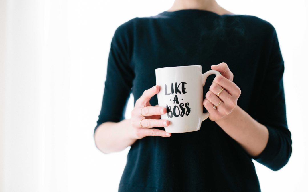 Frau hält Tasse mit Like a boss in der Hand