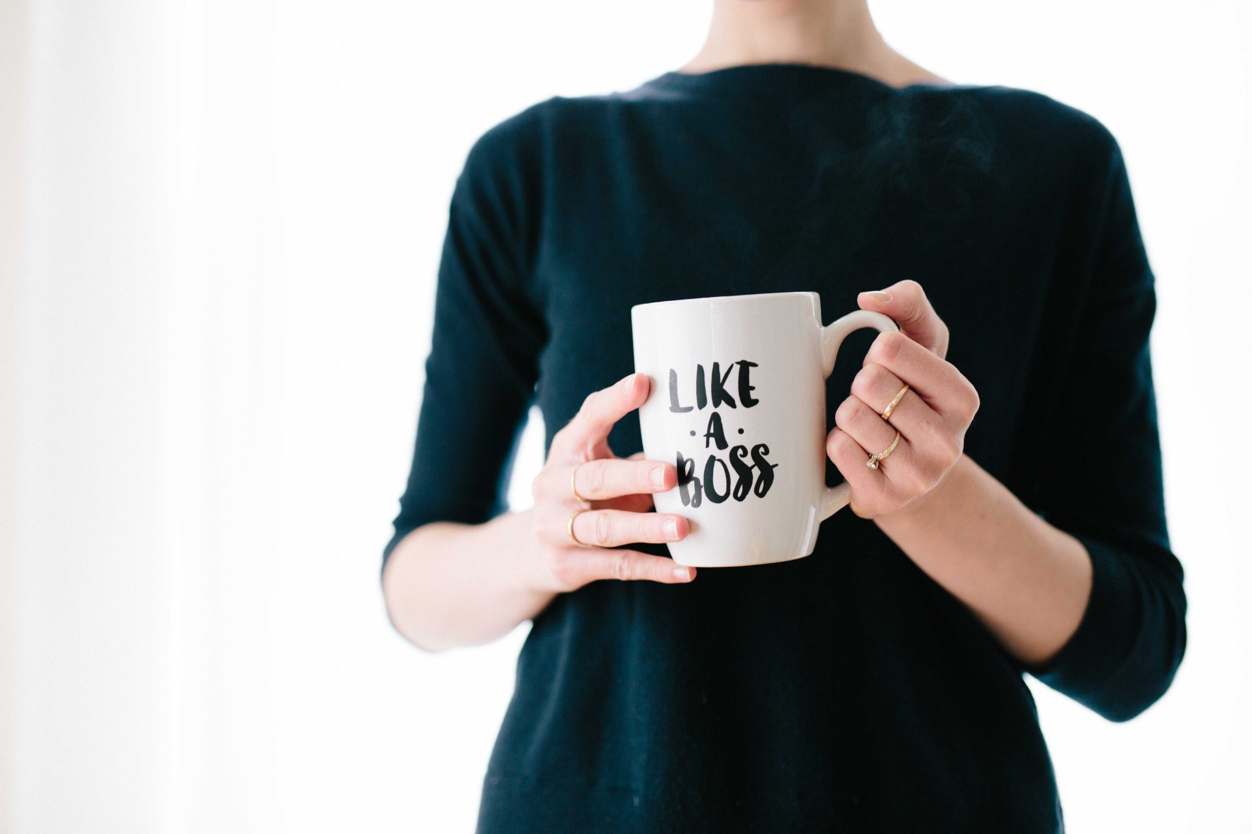 Frau hält Tasse mit Like a boss in der Hand