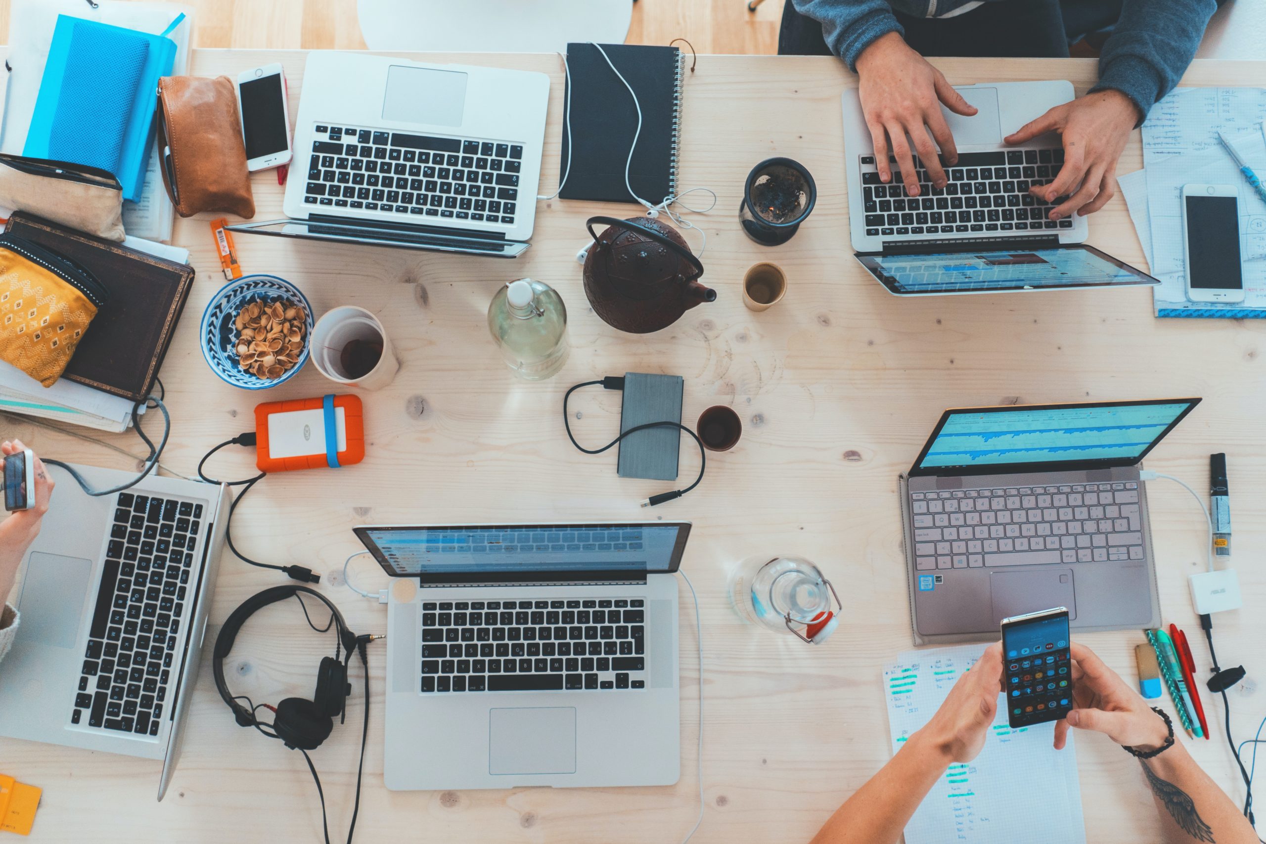 Mitarbeiter sitzen mit Laptops und Handys zusammen an einem Tisch