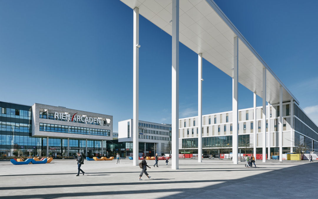 Blick auf den Platz vor den Riem Arcaden mit Menschen, die darüber schlendern