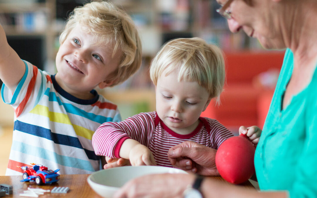 Frau mit zwei Kindern spielt am Tisch