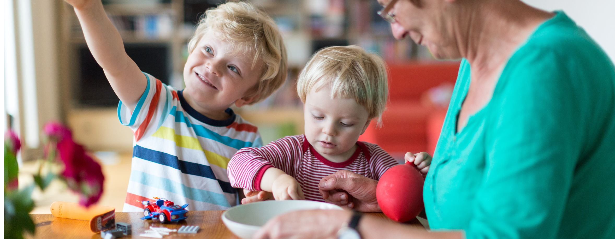 Frau mit zwei Kindern spielt am Tisch