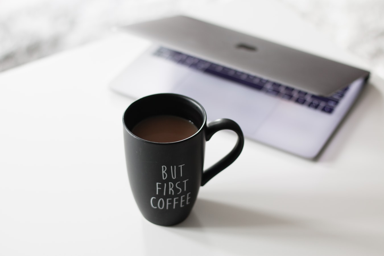 Kaffeetasse steht vor zugeklappten Laptop