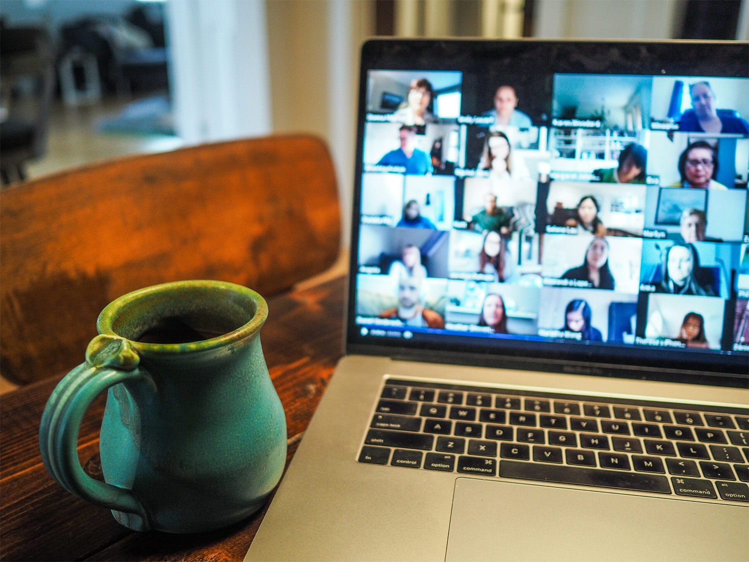 Eine Tasse und ein Kaptop, auf dem eine digitale Konferenz stattfindet