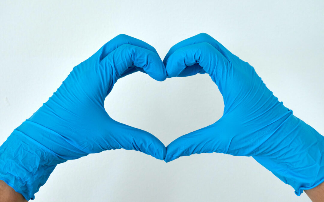 Zwei Hände mit medizinischen Handschuhen formen ein Herz