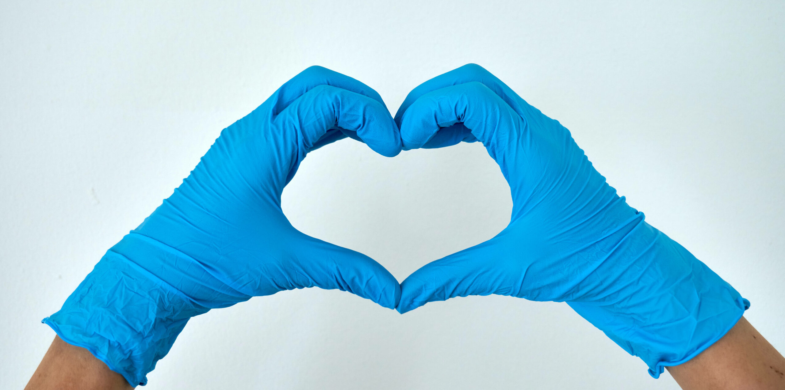 Zwei Hände mit medizinischen Handschuhen formen ein Herz