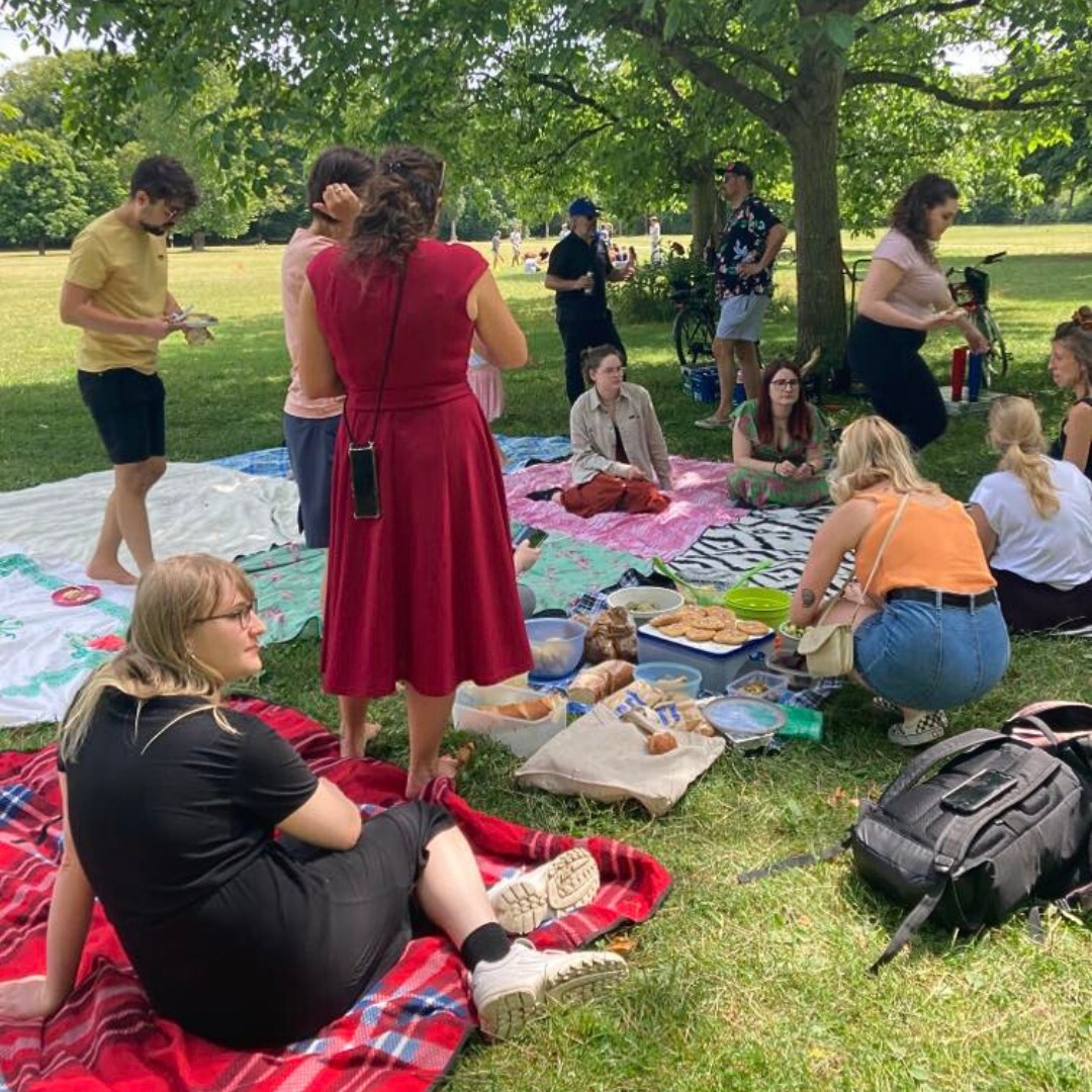 Die ganze .FACTUM Crew sitzt bei unserem Sommerfest im Englischen Garten auf bunten Picknickdecken.