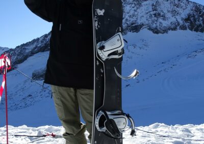 Snowboardfahrer auf der DOUBLEDECK® Evolution-Tour mit Board in der Hand.